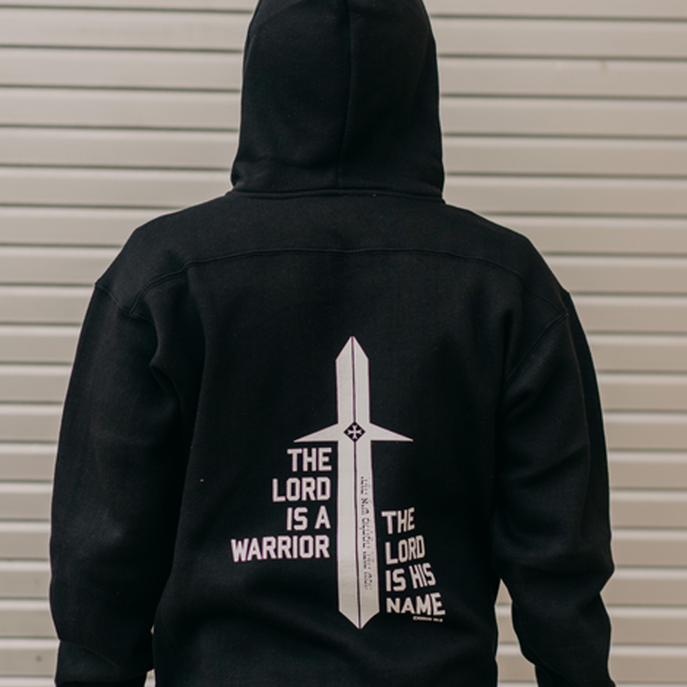 Back view of a person wearing a hooded sweatshirt that reads 'The Lord is a Warrior' with a sword graphic and 'The Lord is His Name' on either side.